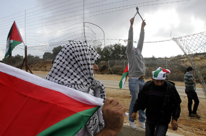 Palestinian activist cuts a barbed wire fence during a protest against Israeli occupation of the West Bank